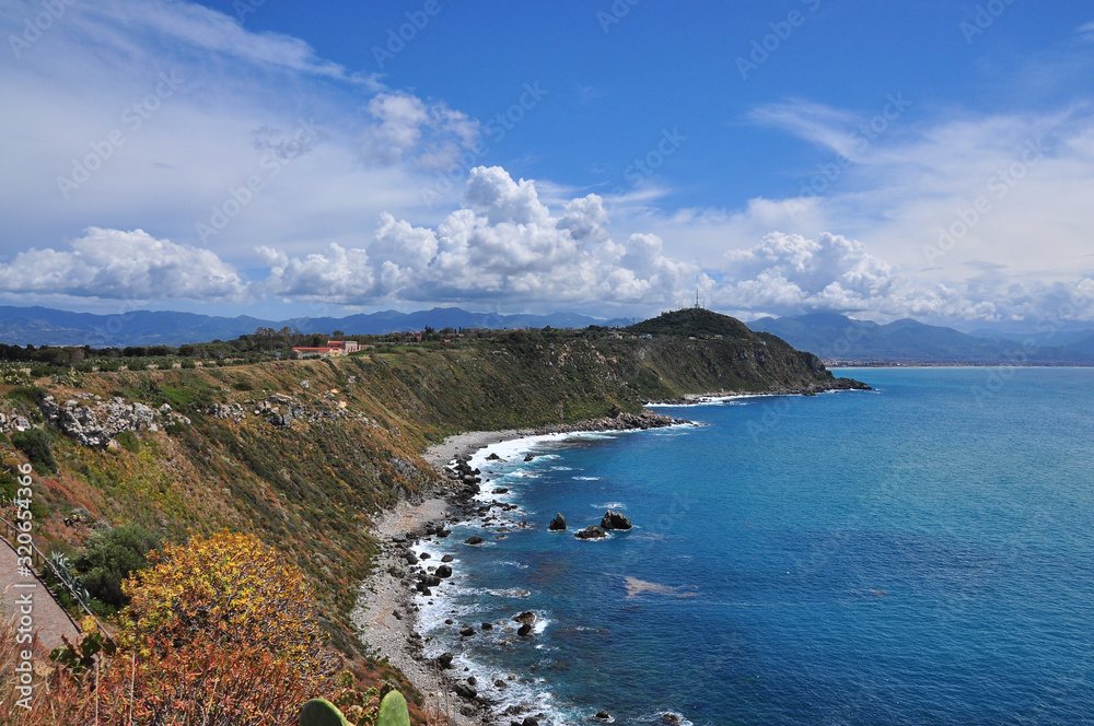 Views of the landscape of San Antonio Bay in Capo Milazzo. Blue sea, cliffs and clouds in the background Milazzo, Sicily, Italy