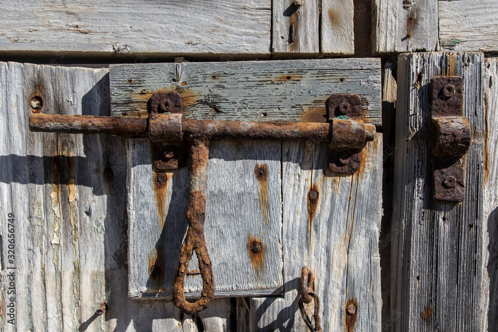 rusty old slide bolt or tower bolt on a wood antique door, old lock, rusty padlock on a wooden door rusty old slide bolt or tower bolt on a wood antique door, old lock, rusty padlock on a wooden door