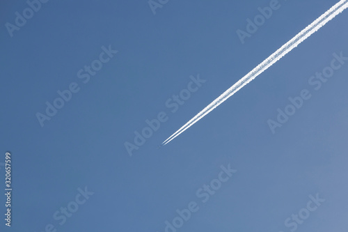 Airplane flies in the blue sky leaving its wake