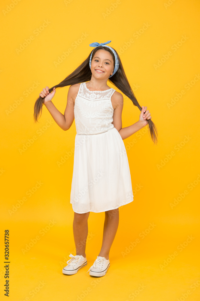 Beautify your hairstyle. Happy girl wear long hairstyle yellow background. Little child hold brunette hair. Gorgeous hairstyle. Beauty hair salon. Fashion hairstyle, stylish look Beautify your hairstyle. Happy girl wear long hairstyle yellow background. Little child hold brunette hair. Gorgeous hairstyle. Beauty hair salon. Fashion hairstyle, stylish look