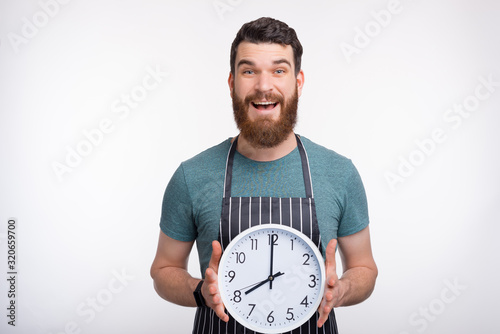 Portrait of young cheerful Chef holding big white watch