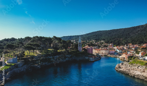 Panoramic aerial photo of the village of Veli Losinj in the Croatian island. View towards the port or marina of the village. Beautiful colorful houses and church are seen. © Anze