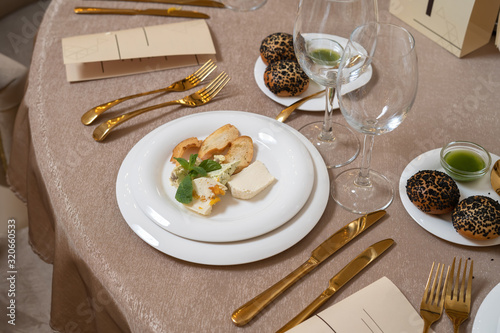 Chic and elegant, gold-plated cutlery and white plates. On the plate are several types of cheese.
