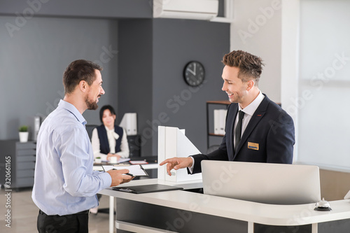 Photo Male receptionist working with visitor in office