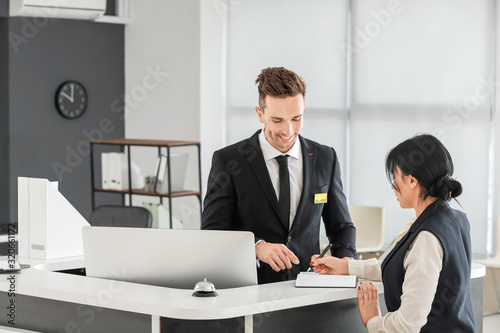 Male receptionist working with visitor in office photo