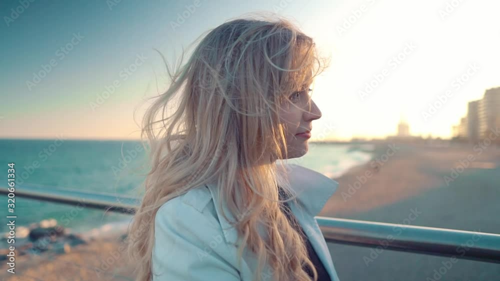 Woman walking along beautiful beach bridge terrace at sunset. The concept of relaxation, happiness and freedom. Woman walking along beautiful beach bridge terrace at sunset. The concept of relaxation, happiness and freedom.