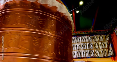 Bhuddhist prayer wheel golden inscribed with a sanskrit prayer and creamy bokeh . photo