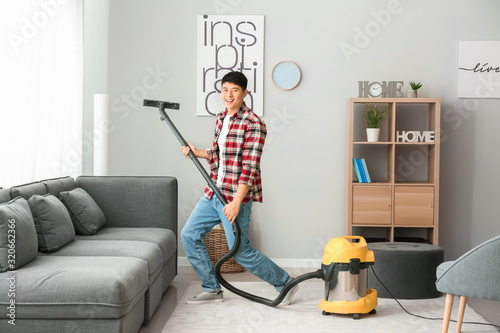 Young Asian man having fun while cleaning floor at home