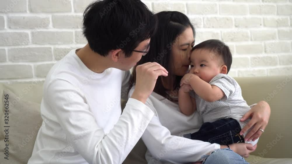 Asian family of father and mother playing with their son on couch at home. Parents and kid enjoying family time. Asian family of father and mother playing with their son on couch at home. Parents and kid enjoying family time.