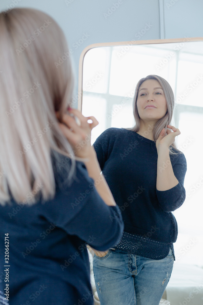 blondie woman near the mirror in minimalistic apartment and posing
