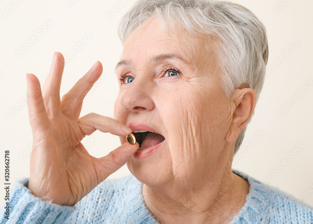 Senior woman with fish oil on white background Senior woman with fish oil on white background