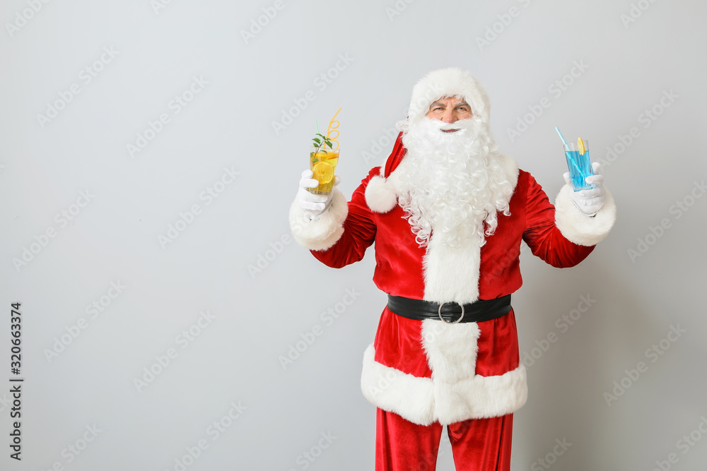 Santa Claus with cocktails on light background. Concept of vacation