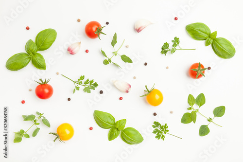Fresh cherry tomatoes, oregano, basil, parsley, garlic, peppercorns on white background. Top pattern. Top view.