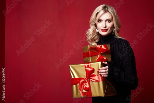 Beautiful young pretty woman bright evening make-up of shiny red lipstick on the lips blond curly hair festive mood knitted winter Christmas New Year and birthday St. Valentine's Day gift surprise.