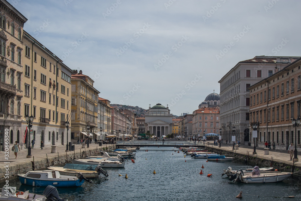 Famous ponte rosson in trieste, canal with boats, looking towards the red bridge and church of Antonio Taumaturgo on a sunny day.