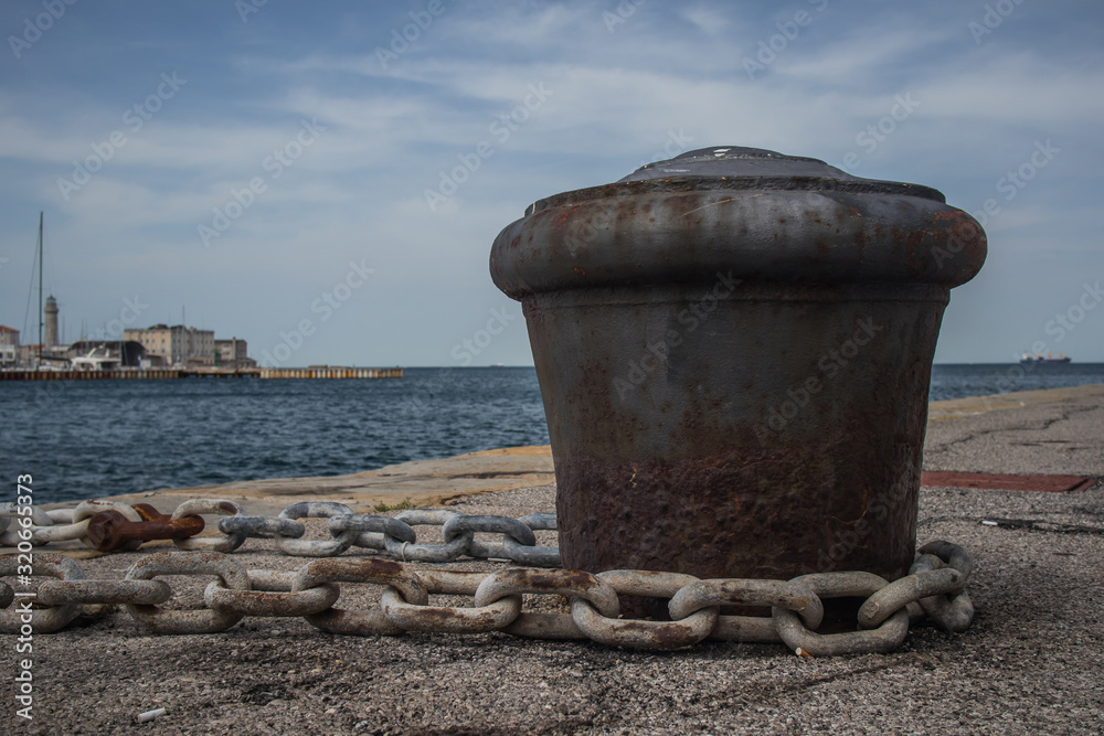 Old metal rusty mooring bollard with a chain wrapped around. Old metal rusty mooring bollard with a chain wrapped around.