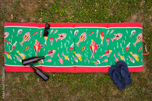 Top view of a vintage retro beach matress with blue sandals, bottles of beer and sunglasses. Concept of a vintage beach accessories looking from above. photo