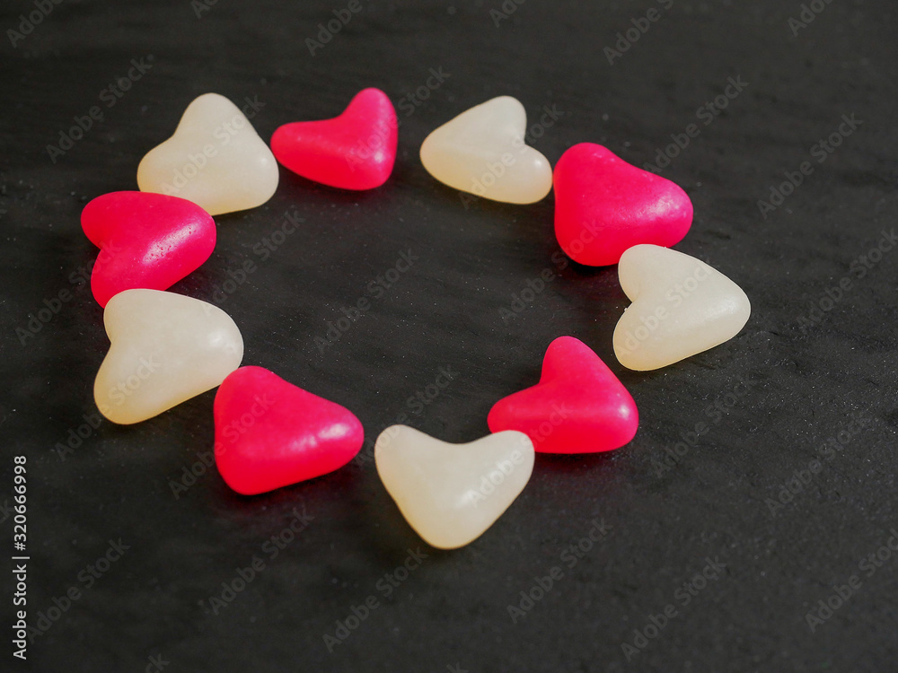 Obraz premium Red and white jelly hearts on dark background. Abstract love and Saint Valentine background.
