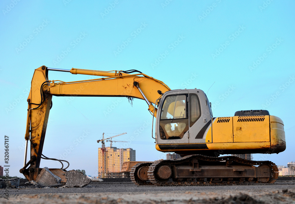 Crawler excavator with hydraulic hammer for the destruction of concrete and hard rock at the construction site. Replacing a concrete runway or road surface at an airport. Roadworks background 