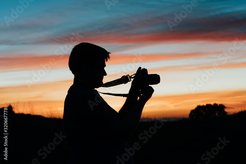 A man taking pictures with his analog camera in a sunset at golden hour