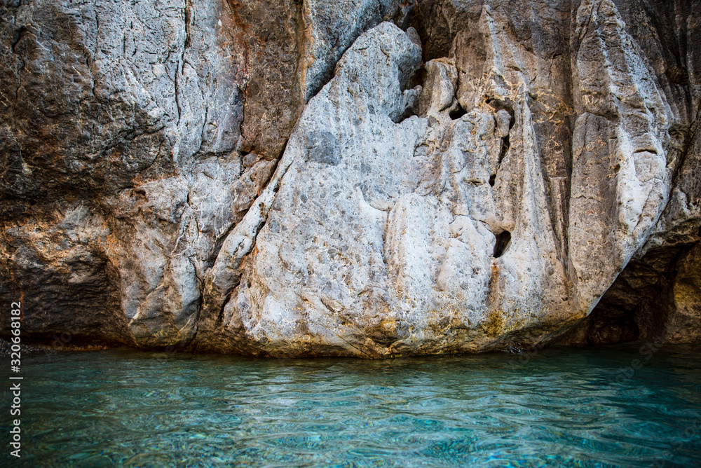A giant cliff rises from transparent turquoise sea water. Majesty and beauty of nature. Rocky mountains in Sa Calobra, Majorca, Spain A giant cliff rises from transparent turquoise sea water. Majesty and beauty of nature. Rocky mountains in Sa Calobra, Majorca, Spain
