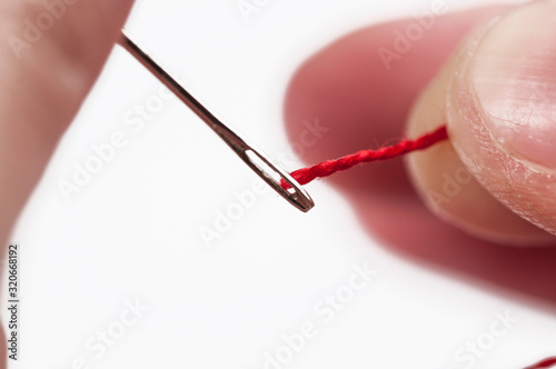 Needle and thread in woman's hand isolated on white background.Copy space