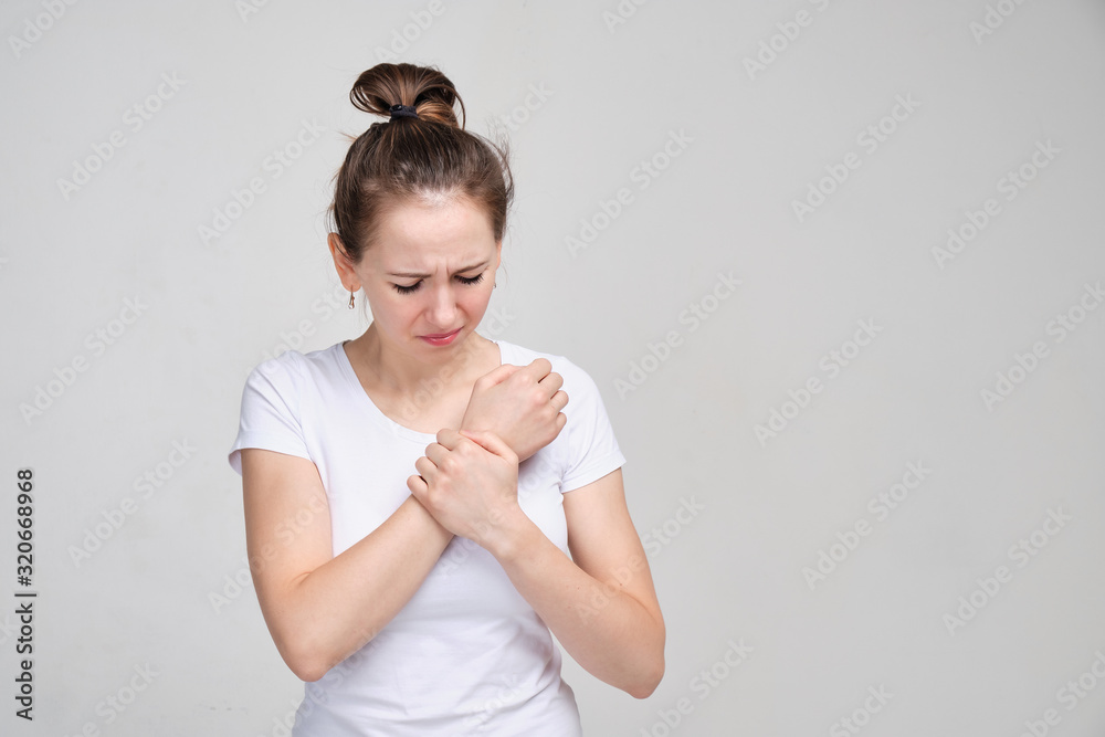 Obraz premium Girl in a white T-shirt massages a brush. Concept of joint pain. close up.