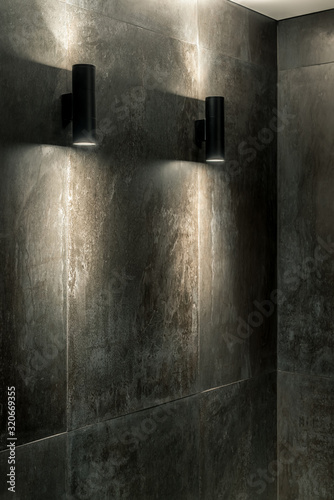 Luminous black lamps on tiled wall indoors