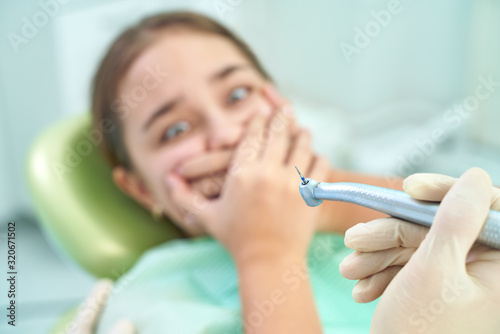 Girl sitting at dental chair with open mouth during oral check up while doctor. Visiting dentist office. Dentistry concept.