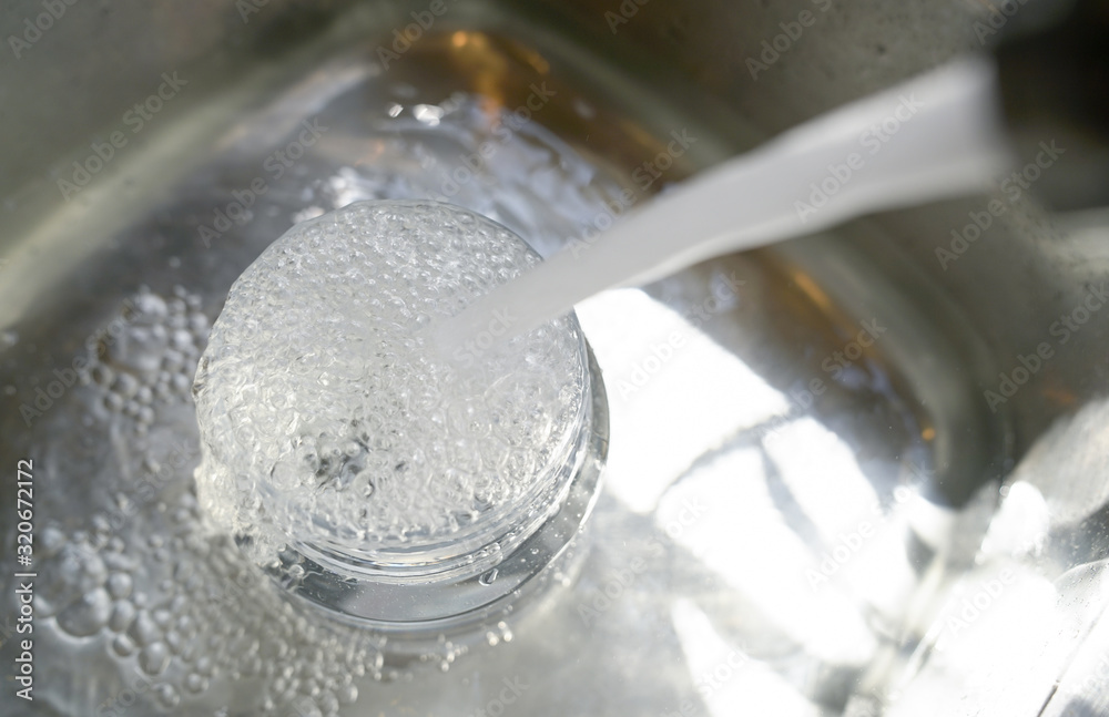 Water from tap into plastic container and overflow to the sink. Water from tap into plastic container and overflow to the sink.