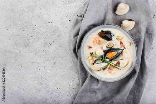 Clam chowder in a gray plate. The main ingredients are shellfish, broth, butter, potatoes and onions. photo