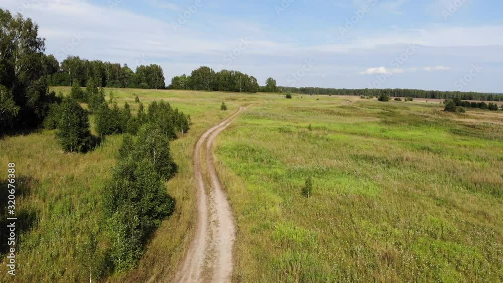 Aerial fly over rural dirt road in forest along margins in summer Sunny day Aerial fly over rural dirt road in forest along margins in summer Sunny day