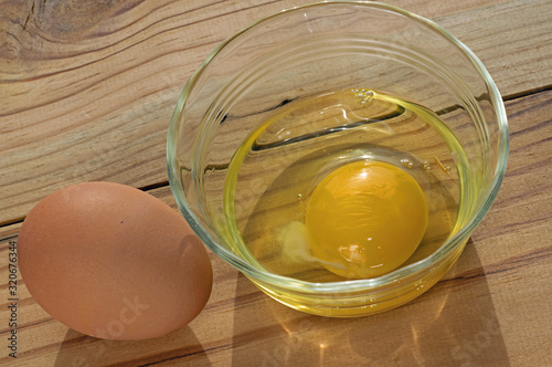 Brown chicken egg in shell and broken reading for cooking. Egg yolks and whole eggs store significant amounts of protein and choline and are widely used in cookery. photo