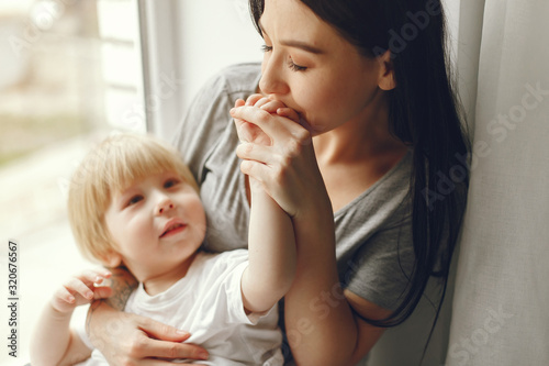 Beautiful woman with child. Woman in a gray t-shirt. Family sitting on a windowsill.