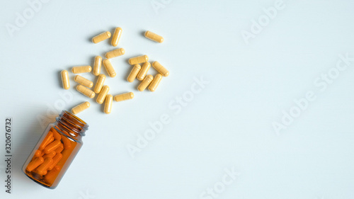 Foto Herbal pills in capsules spilling from glass bottle