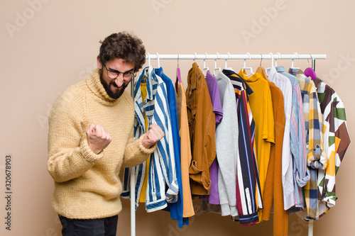 young cool berded man with clothes against flat wall photo