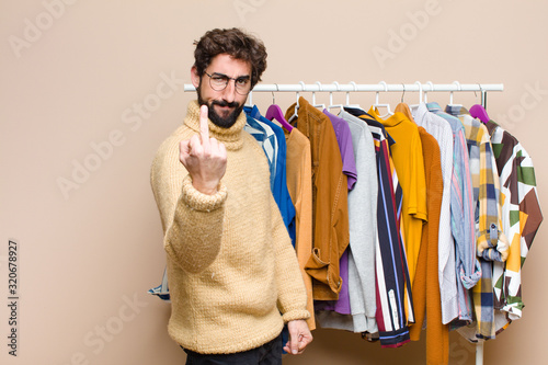 young cool berded man with clothes against flat wall photo