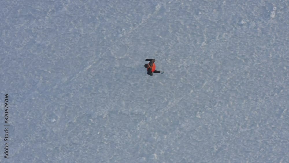 Top aerial view of a man running on ice of frozen Amur bay in winter. Vladivostok, Russia Top aerial view of a man running on ice of frozen Amur bay in winter. Vladivostok, Russia