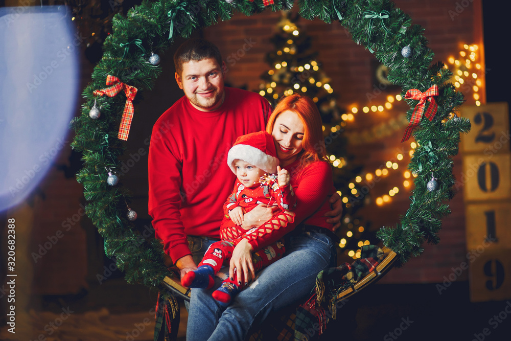 Beautiful mother in a red sweater. Family sitting near christmas gifts. Little boy near christmas tree Beautiful mother in a red sweater. Family sitting near christmas gifts. Little boy near christmas tree