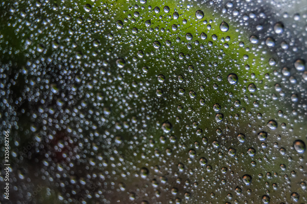 Abstract rain drops pattern on glass window of car with green reflection of plant Abstract rain drops pattern on glass window of car with green reflection of plant