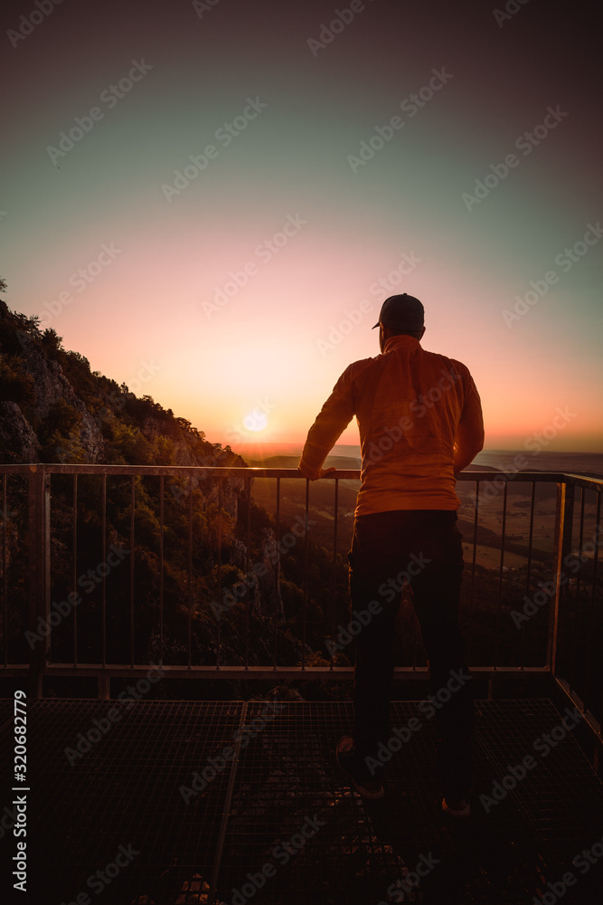 Fototapeta premium Man on top of mountain watching the sunrise . Conceptual scene.
