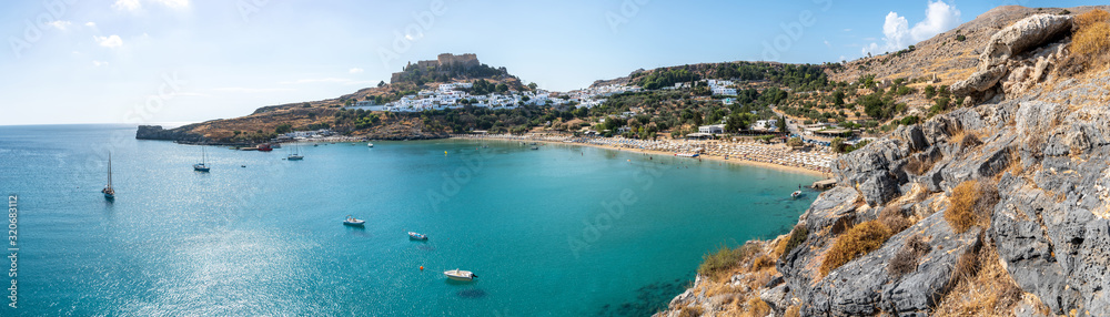 Lindos bay with famous beach and village of Lindos and Acropolis in background – panoramic (Rhodes, Greece)