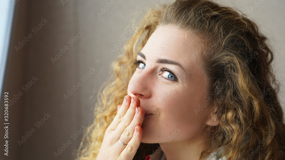 emotion of a beautiful curly girl on a gray bokeh background. surprise, smile, secret. portrait of a blonde young lady model emotion of a beautiful curly girl on a gray bokeh background. surprise, smile, secret. portrait of a blonde young lady model