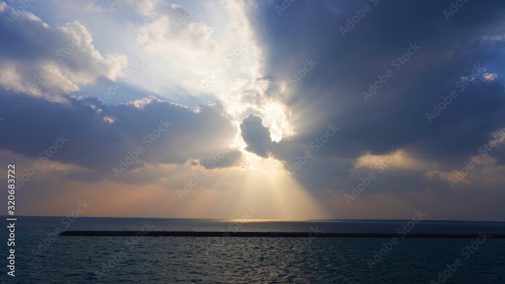 blue sky in the clouds. sunset sky, yellow white rays of the sun shine through the clouds on the ocean. sunset on the open sea, paradise. glow from heaven. cloudy sky