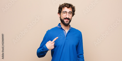 Foto young handsome man looking proud, confident and happy, smiling and pointing to s