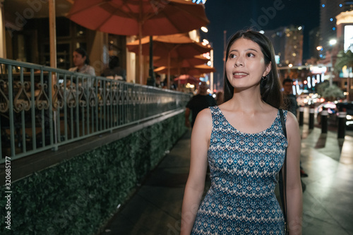 Attractive woman traveler walk through streets at night. beautiful smiling lady tourist relax on road with outdoor cafe aside. charming female visitor in city urban modern las vegas nevada usa.