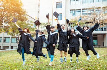 happy  students in graduation gowns celebrating and jumping  in  university campus
