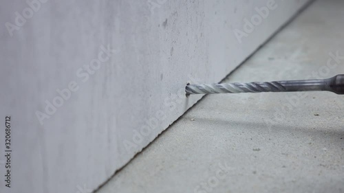 Close up on makes a hole in a concrete wall with hammer drill