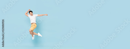 Obraz na plátne Happy Asian man smiling and jumping on blue banner background