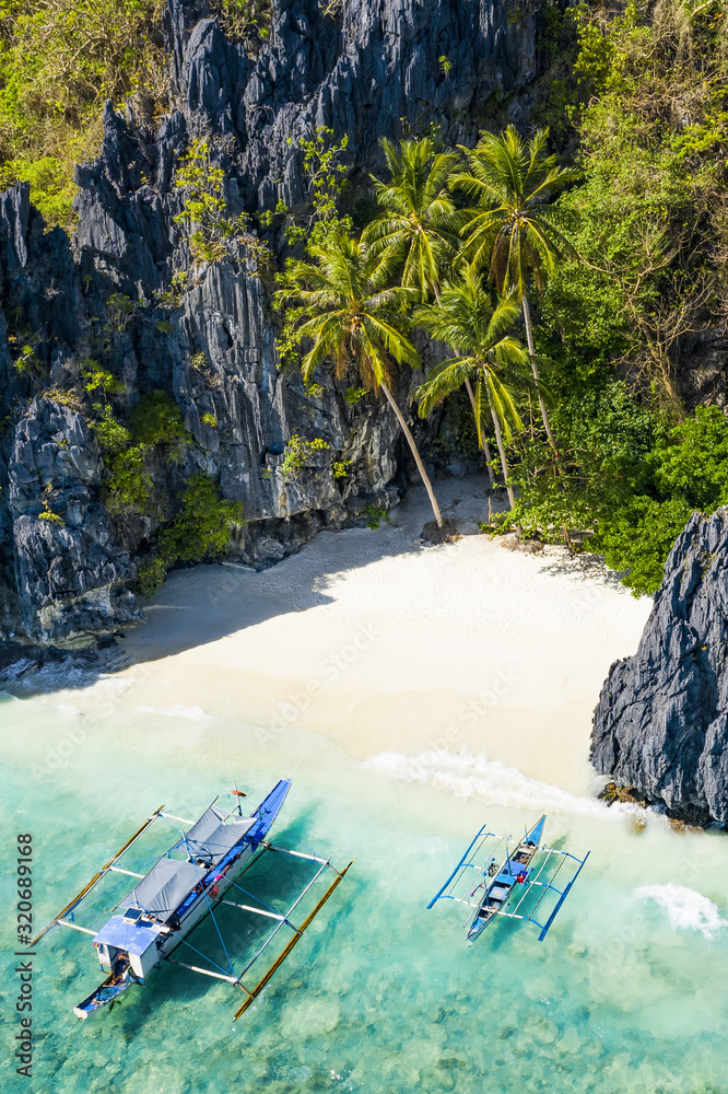 View from above, aerial view the Entalula Beach, a white sand beach surrounded by rocky formations and bathed by a crystal clear sea. Entalula island, Bacuit Bay, El Nido, Palawan, Philippines.